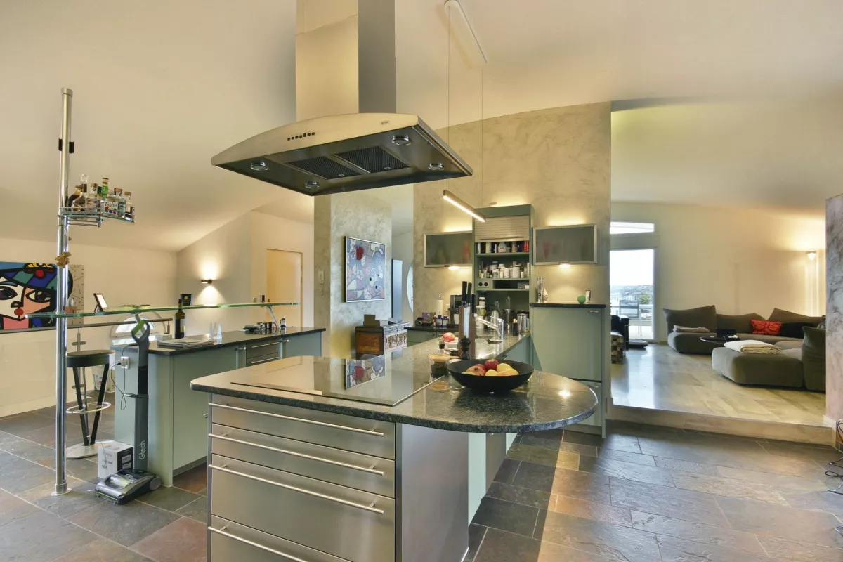 Moderne offene Küche in Metalfarbe mit Dunstabzugshauben an der Decke, LED-Spots in die Küchenwand integriert, Essbar mit Hockern, Hintergrundblick auf das Wohnzimmer