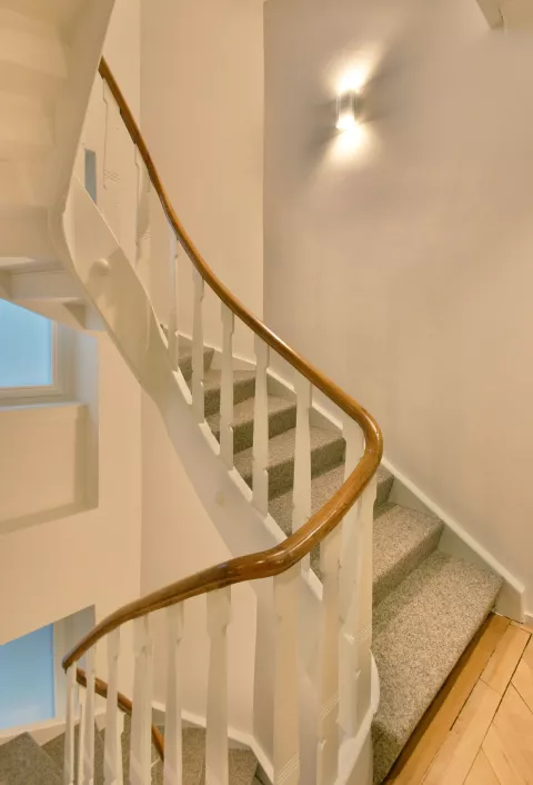 Ansteigende Treppen mit Teppich, Holzzaun, Designerlampe an der Wand 
